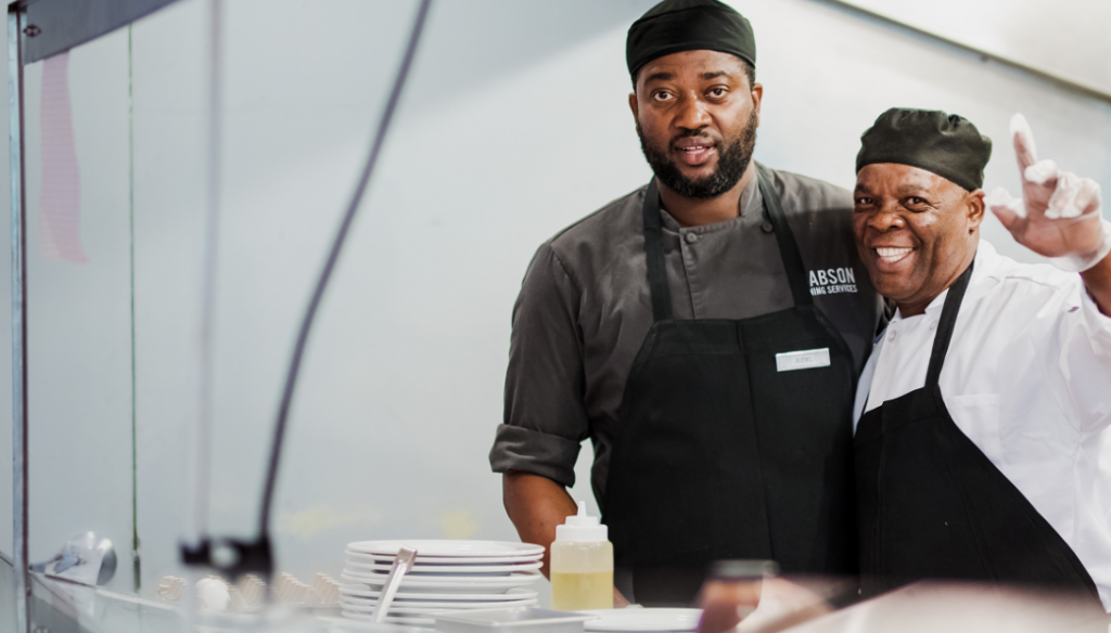 Two men in kitchen smiling