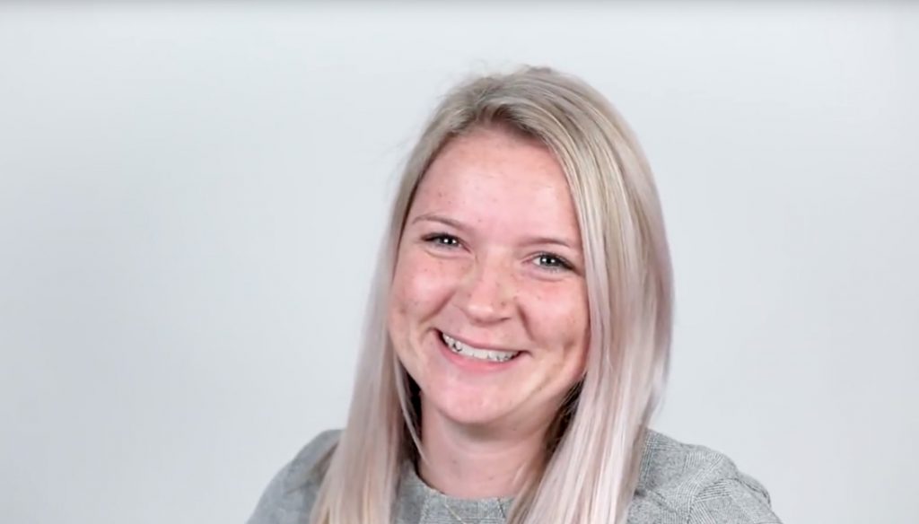 Woman smiling in front of gray background